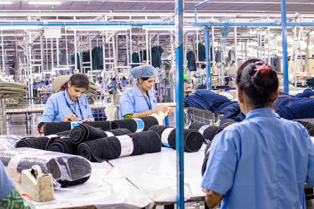 Trabalhadoras separando tecidos em uma grande fábrica têxtil, demonstrando laboriosidade e trabalho em equipe.