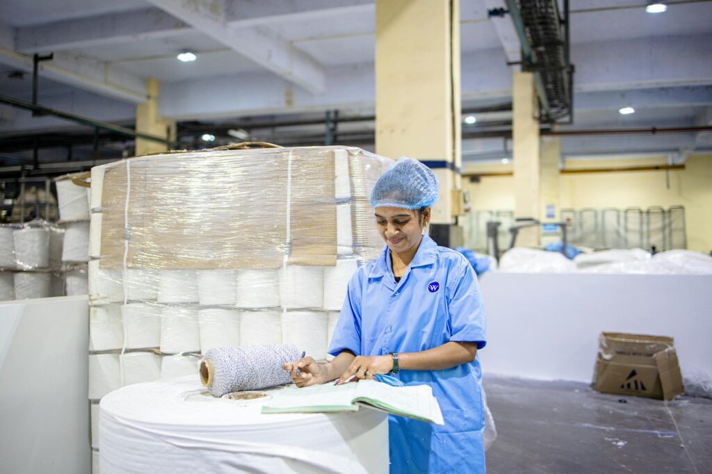 Um operário registra detalhes em uma fábrica de tecidos, demonstrando laboriosidade e precisão.