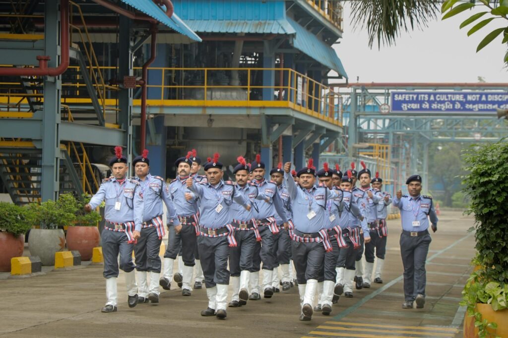Um grupo de seguranças marchando em uma área industrial, demonstrando disciplina e trabalho em equipe.