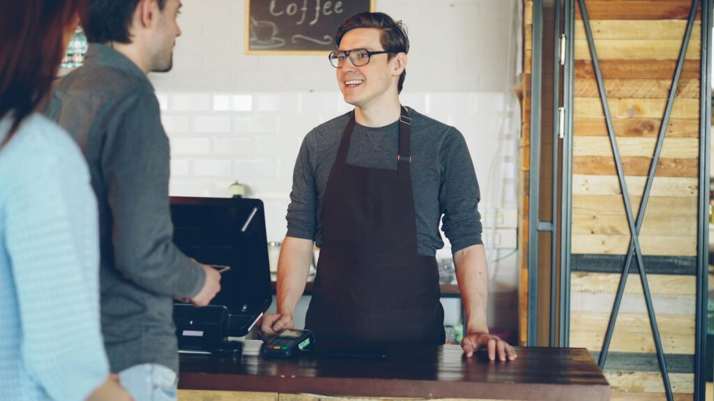 Um barista simpático atende os clientes em um balcão de café aconchegante.