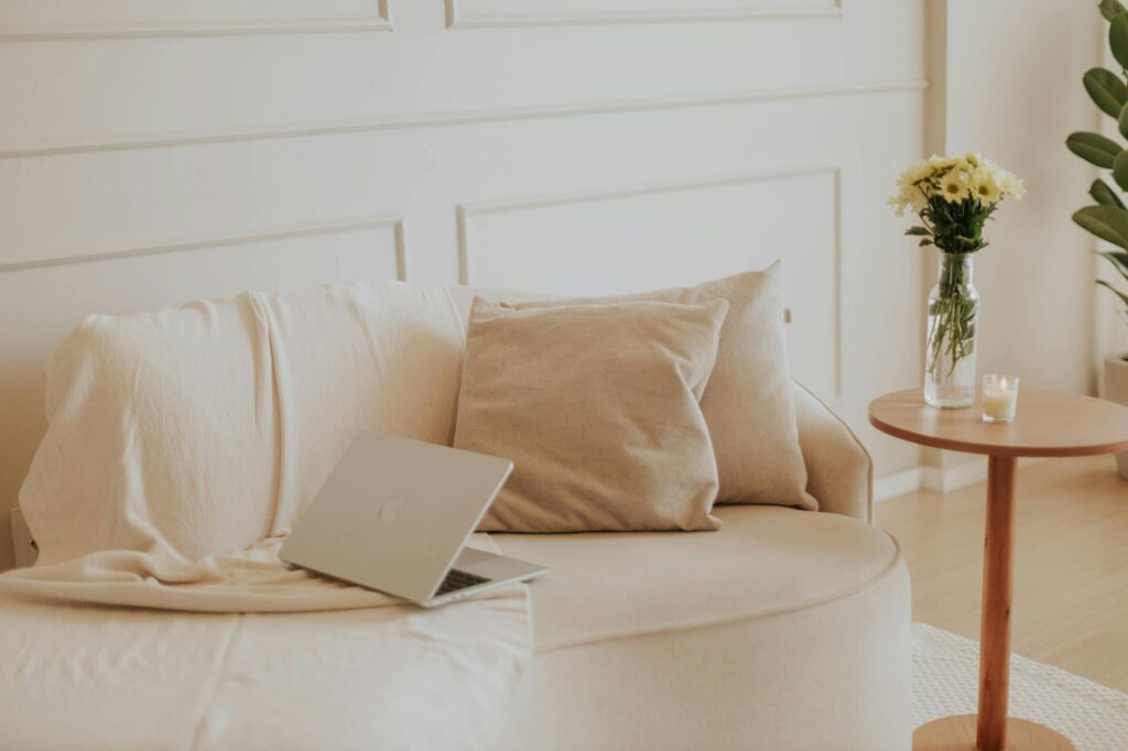 Um espaço de convivência minimalista e sereno com um laptop e flores, perfeito para trabalho remoto.